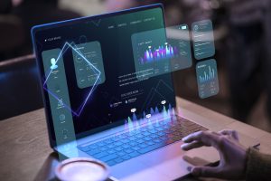 Imagem de uma pessoa interagindo com um laptop que exibe gráficos interativos e painéis de controle digitais, representando o uso de Big Data. O sistema na tela exibe visualizações de dados com gráficos de desempenho, atividades e análise de portfólio, com elementos futuristas como ícones e números flutuantes. A imagem transmite a ideia de análise avançada e tomada de decisões baseadas em grandes volumes de dados, refletindo a importância do Big Data na gestão e interpretação de informações.