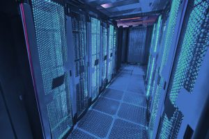 Corredor moderno de um ambiente tecnológico com servidores iluminados por luzes azuis, representando a infraestrutura avançada dos data centers utilizados para armazenamento e processamento de dados em larga escala.